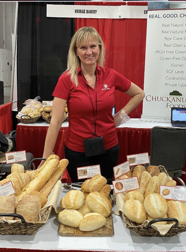 Melissa Calrow, sales representative for Vieira's Bakery, behind a Vieira's Bakery trade show booth with bread