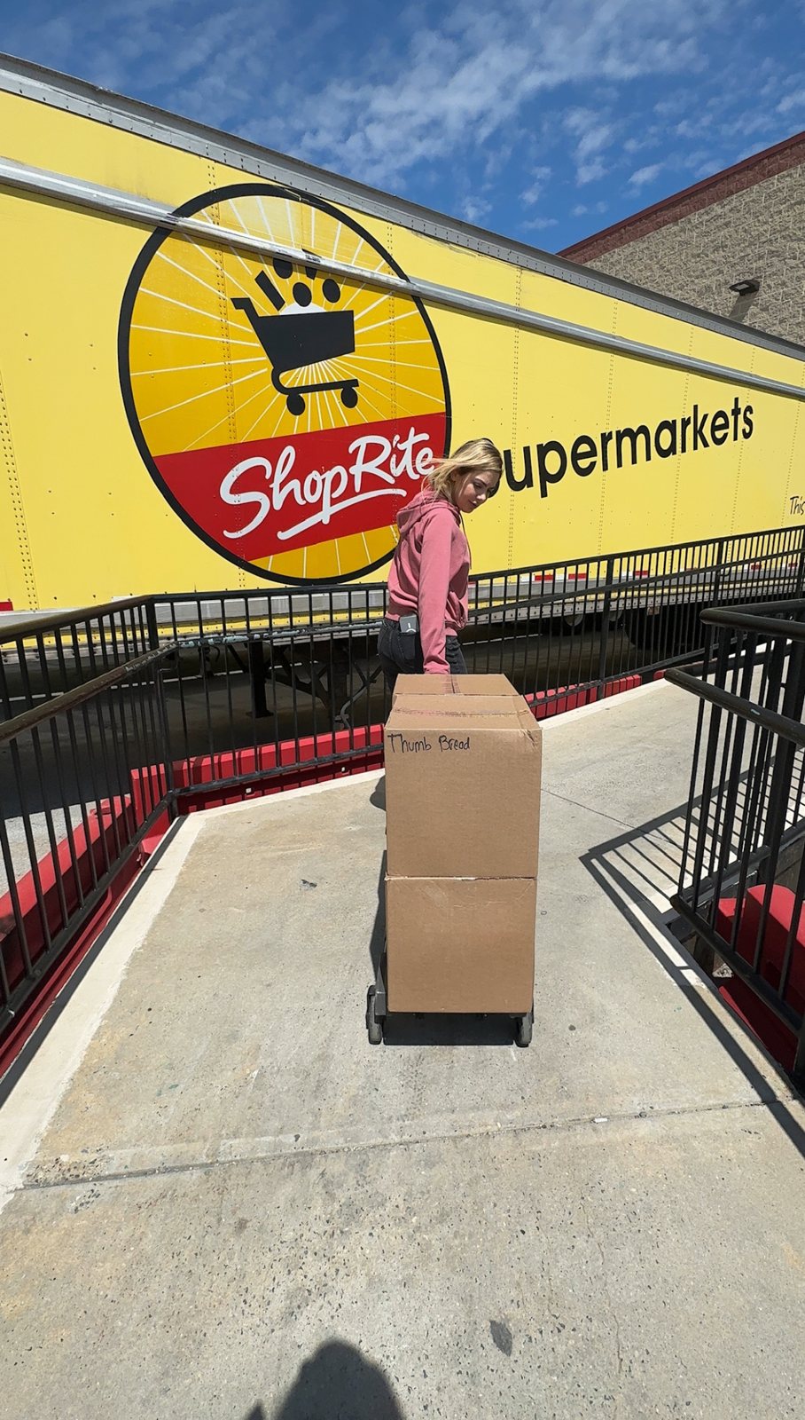 Arzu Esendemir delivering boxes of Thumb Bread® on a hand truck past a ShopRite Supermarkets trailer