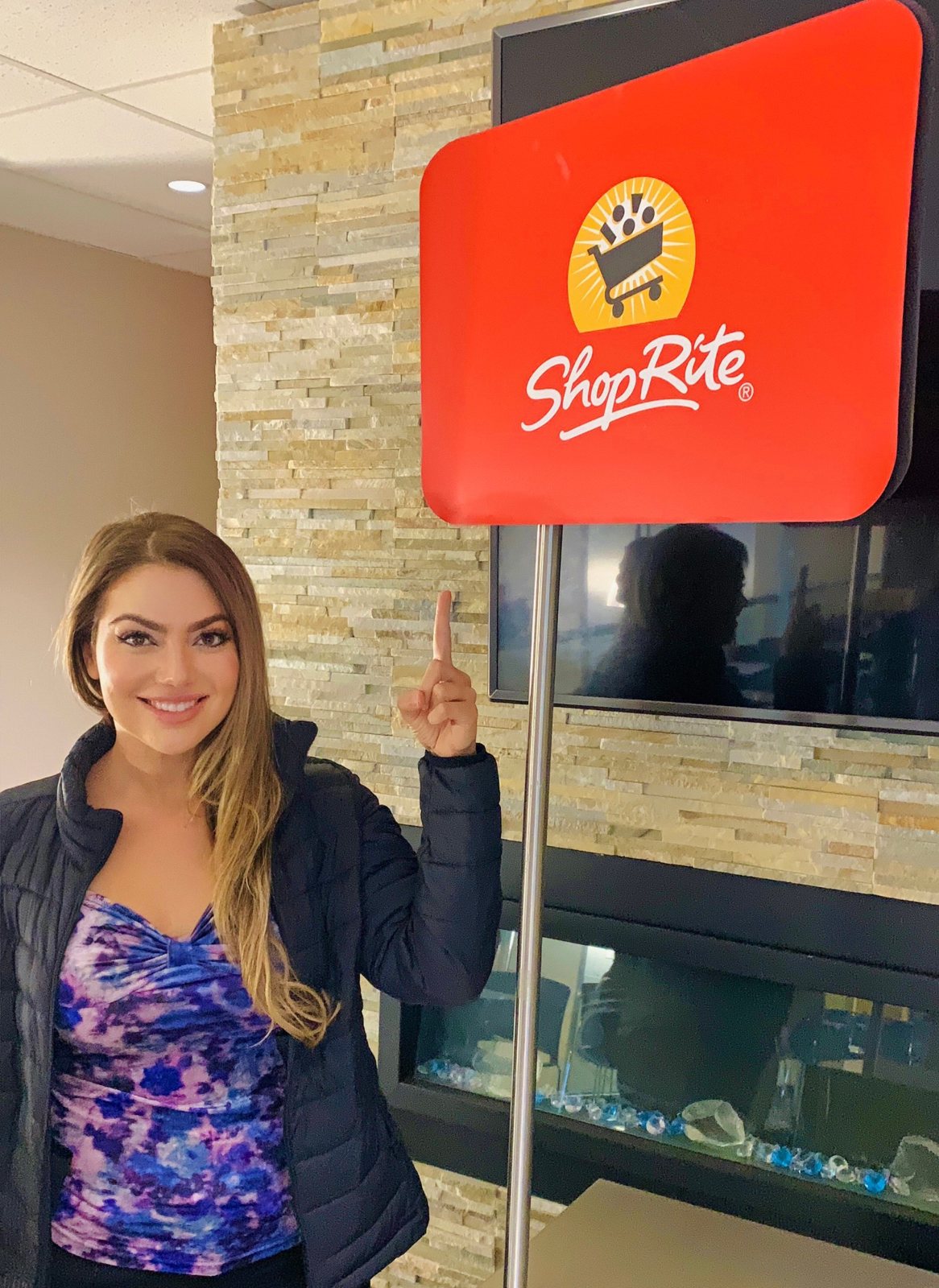 Arzu Esendemir pointing to a ShopRite sign