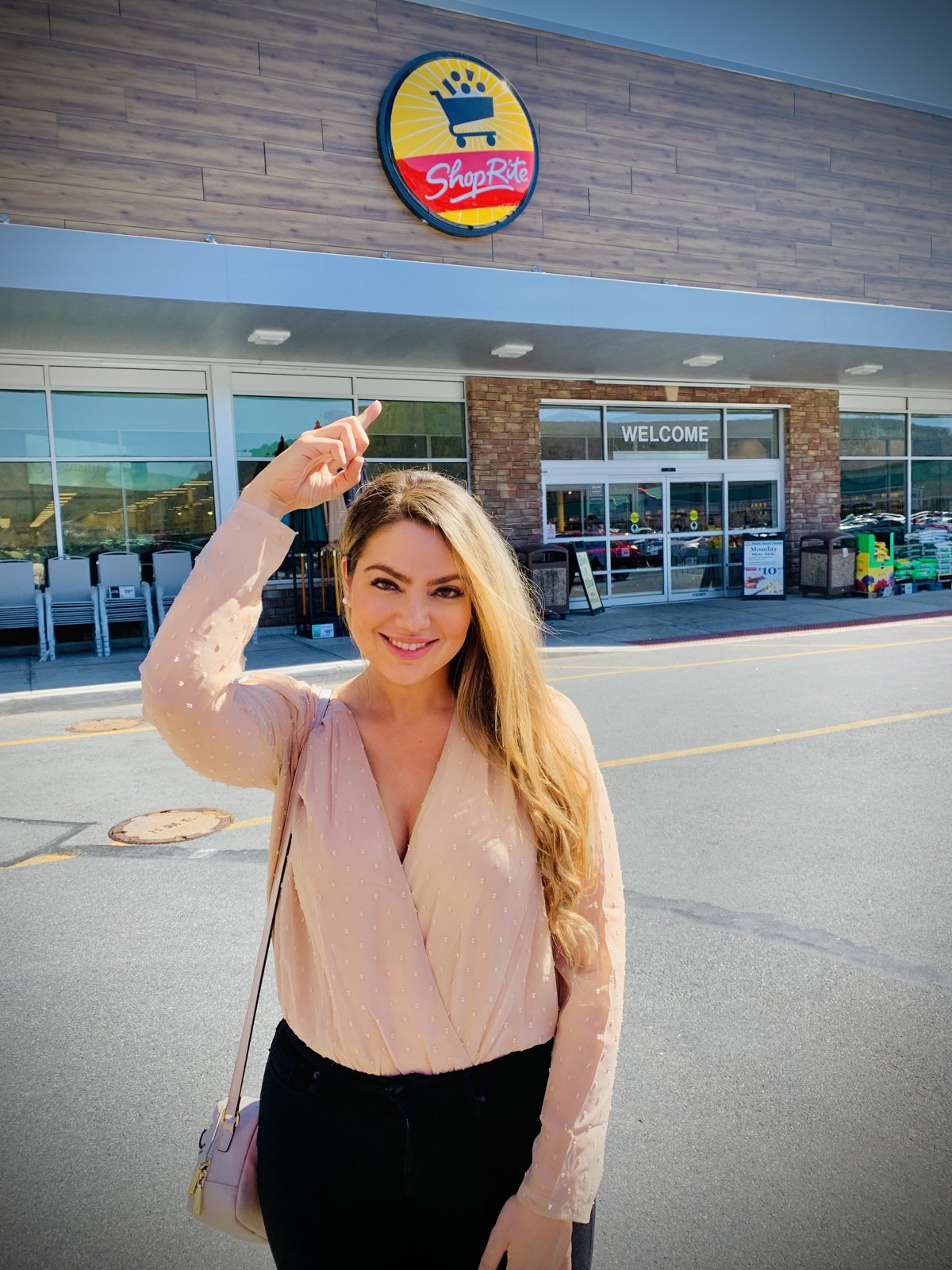 Arzu Esendemir pointing up at the ShopRite sign outside a ShopRite store