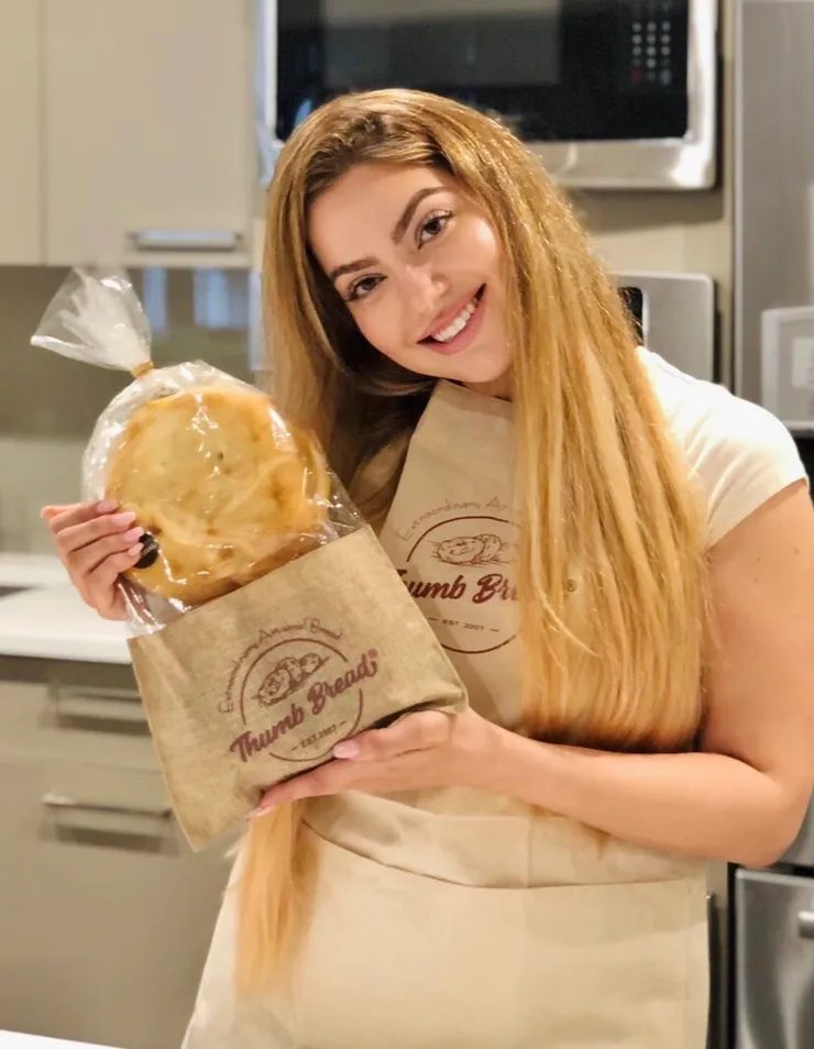 Arzu Esendemir in a Thumb Bread® apron holding a bag of Thumb Bread®