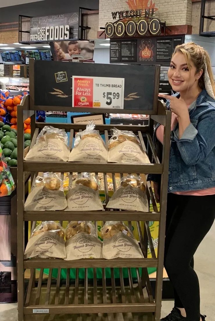Arzu Esendemir next to a Thumb Bread® display rack in a grocery store