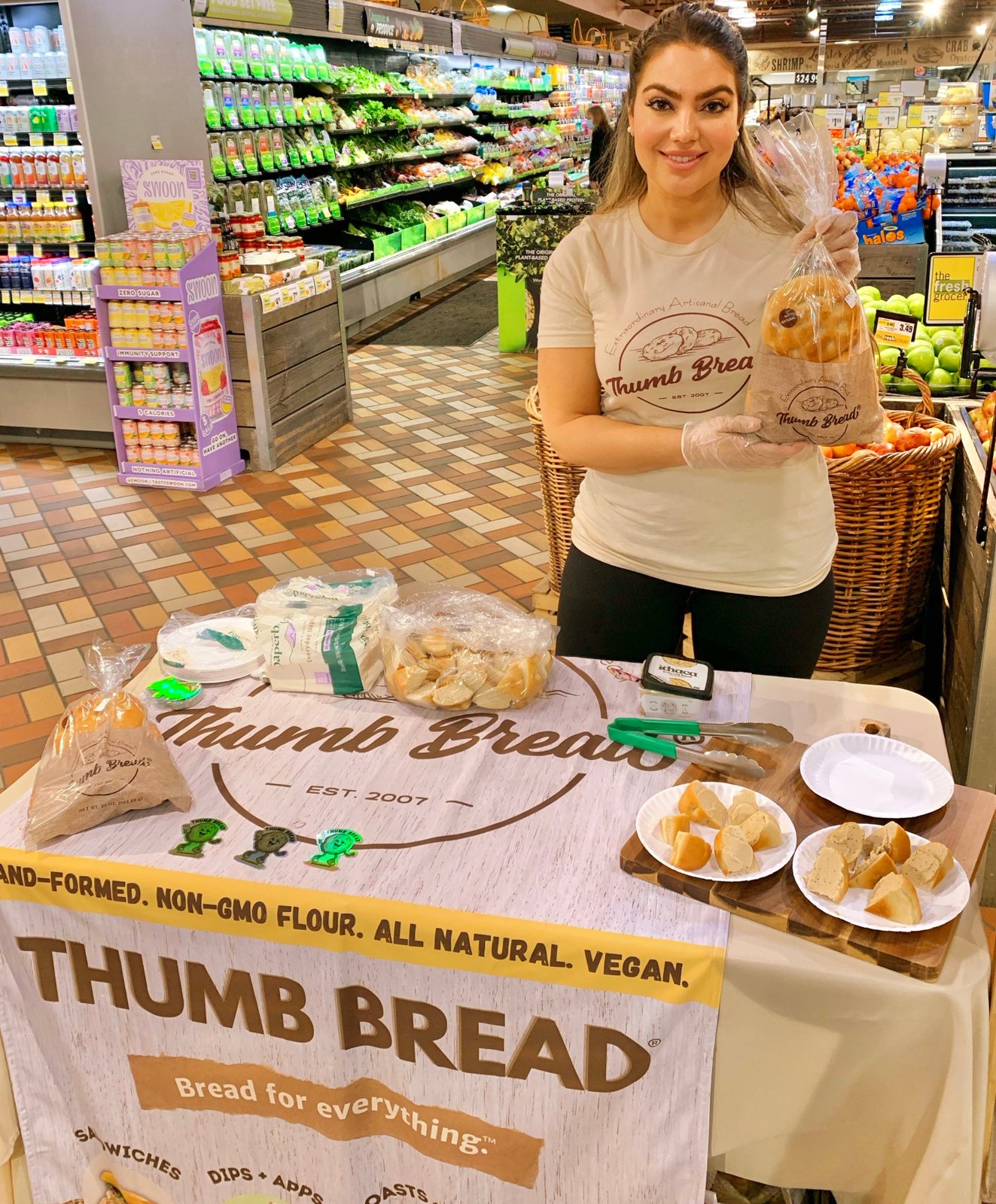 Arzu Esendemir holding Thumb Bread® at a Thumb Bread® tasting table at The Fresh Grocer