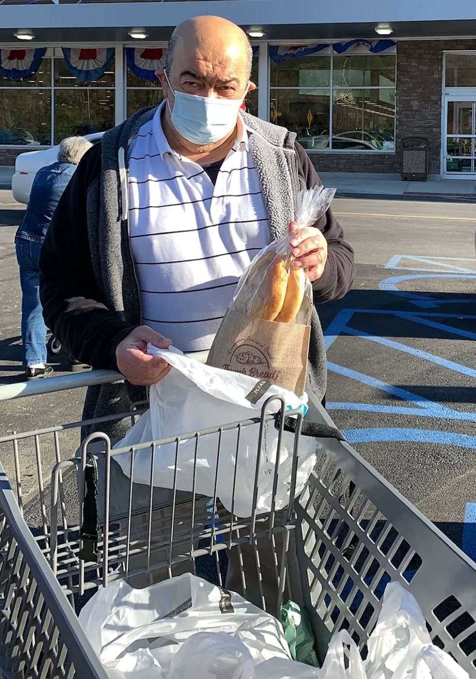 Baba with a grocery cart outside a ShopRite holding a bag of Thumb Bread®