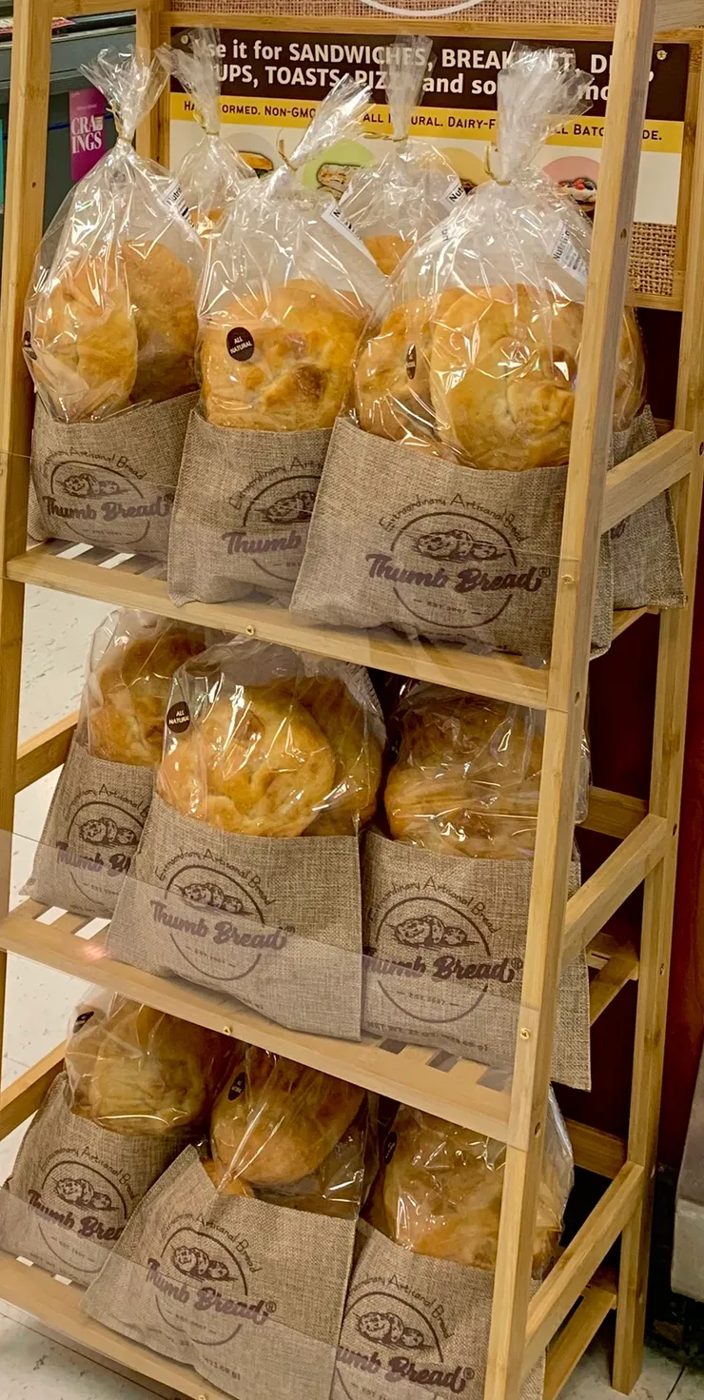 Thumb Bread® in burlap bags on a wooden store display rack