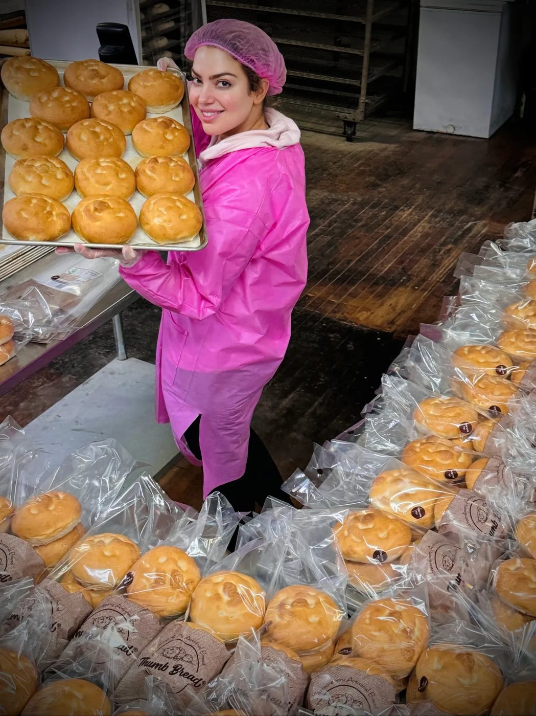 One of the Esendemir sisters in a bakery coat with trays of fresh Thumb Bread®