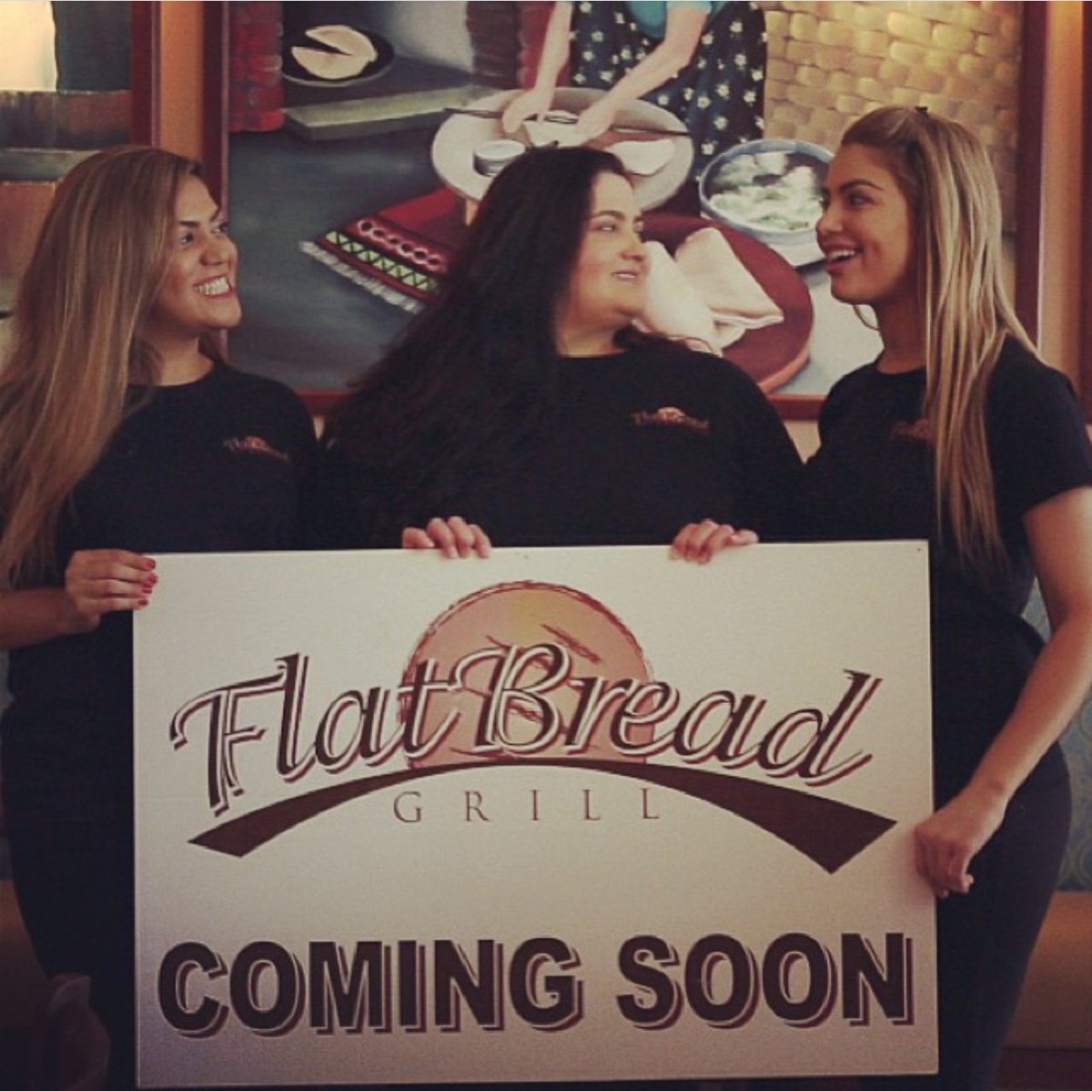 The Esendemir sisters holding a Flatbread Grill® coming soon sign