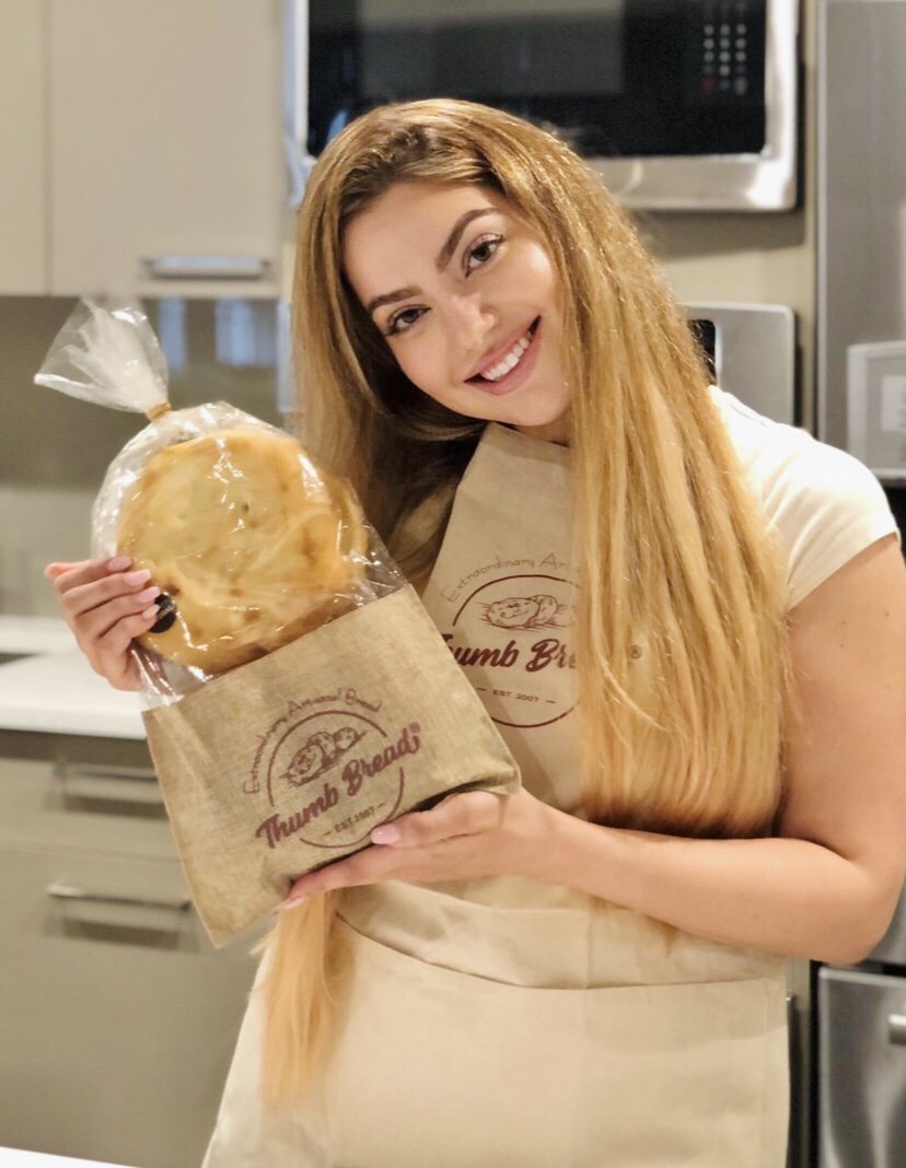 One of the Esendemir sisters in an apron holding Thumb Bread® in the burlap bread bag