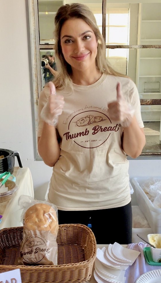 One of the Esendemir sisters in a Thumb Bread® t-shirt giving a thumbs up at a tasting