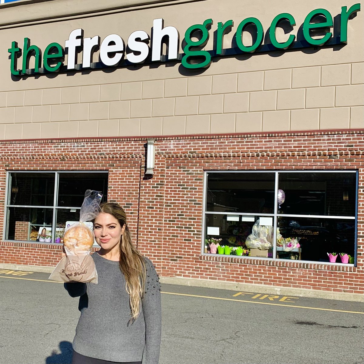 One of the Esendemir sisters holding Thumb Bread® outside The Fresh Grocer